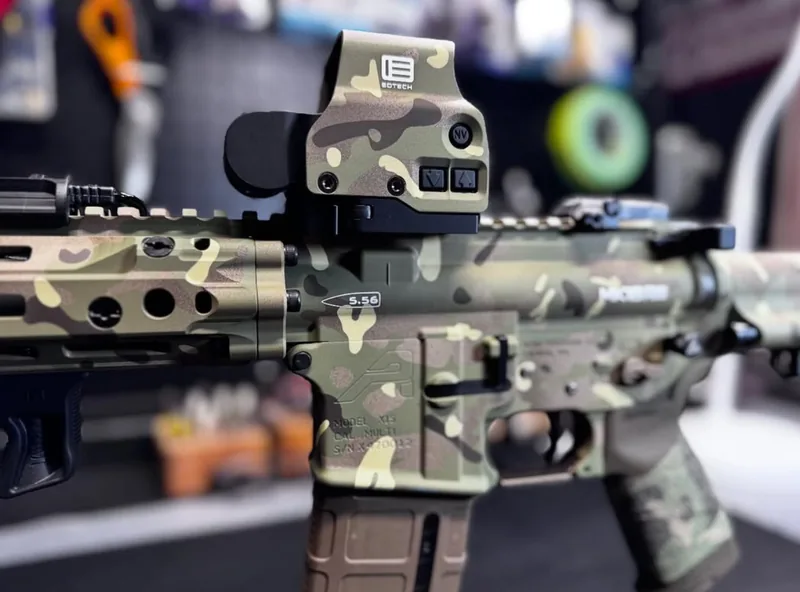 An AR-15 upper and lower finished in multicam Cerakote with a matching optic