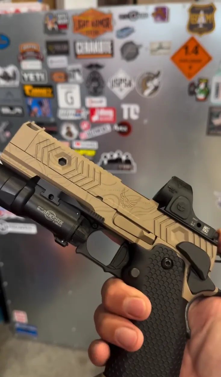 A pistol slide finished in topo camo Cerakote with contour engraving